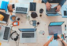 Explaining the Importance of a Service Desk Software for Business people sitting down near table with assorted laptop computers