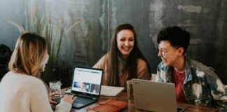 What Is the Benefit of a Cloud LMS three people sitting in front of table laughing together
