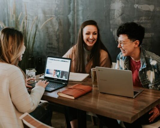 What Is the Benefit of a Cloud LMS three people sitting in front of table laughing together