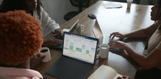 How To Choose Microsoft Business Central Consultants Three people in a meeting at a table discussing schedule on their Microsoft laptop