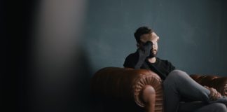 A reliable adviser that helps you make the right decision a man holds his head while sitting on a sofa