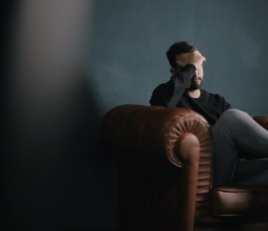 A reliable adviser that helps you make the right decision a man holds his head while sitting on a sofa