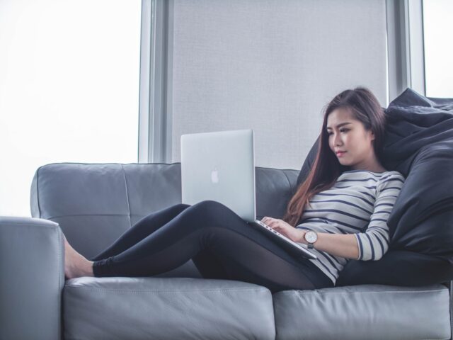 Photo by Mimi Thian woman sitting on sofa while using MacBook Pro