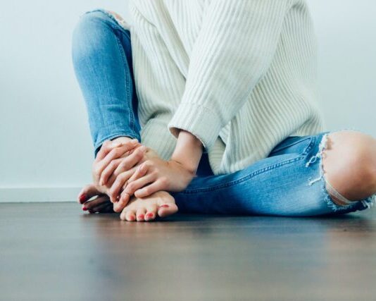 5 Tips for Dealing with Plantar Fasciitis person wearing distressed blue denim jeans inside room