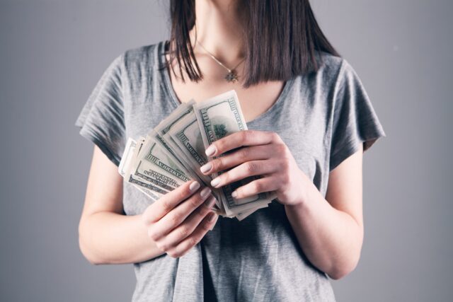 Photo by Sasun Bughdaryan woman in gray shirt holding fan of us dollar bills
