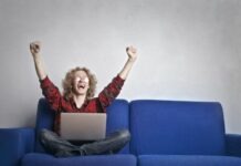 All You Need to Know About Andar Bahar Photo of Excited Person With Hands Up Sitting on A Blue Sofa While Using a Laptop