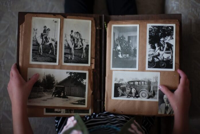 Photo by Laura Fuhrman person opening photo album displaying grayscale photos