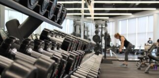 The Best Ways to Increase Exercise Motivation woman standing surrounded by exercise equipment