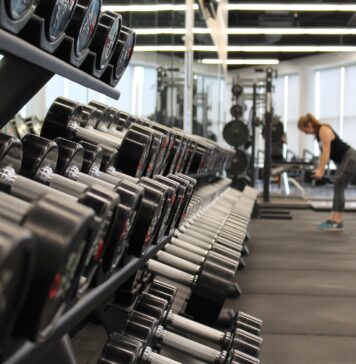 The Best Ways to Increase Exercise Motivation woman standing surrounded by exercise equipment