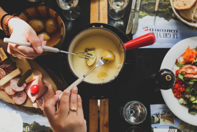 Photo by angela pham two person holding fork dipping food on sauce