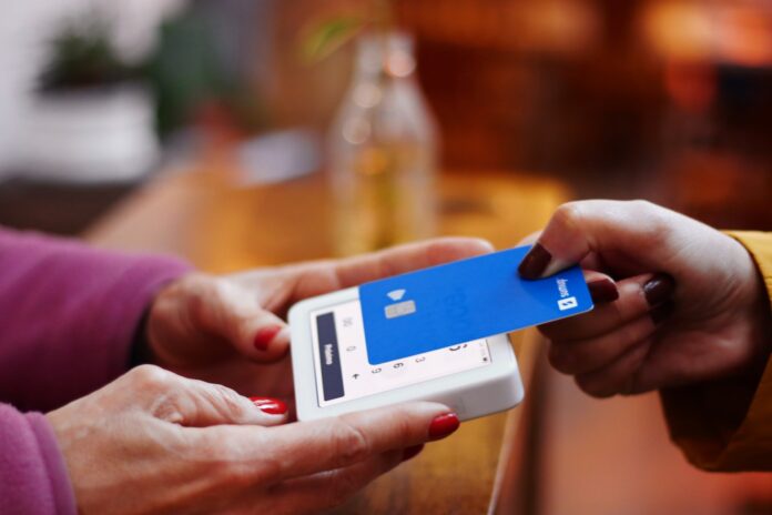 Photo by Nathana Rebouças a person holding a credit card and a cell phone