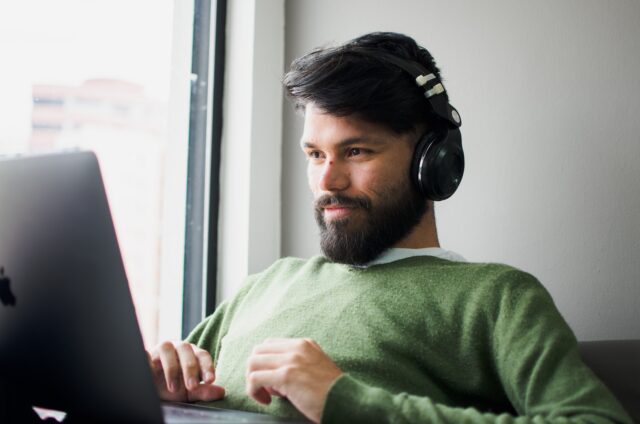 Photo by Miguelangel Miquelena man wearing headphones while looking at MacBook