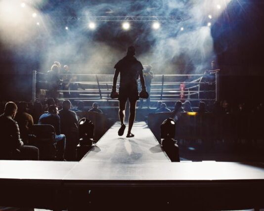 Knockout Wins: Explore the World of Online Boxing Betting at Leon India man standing and walking going on boxing ring surrounded with people