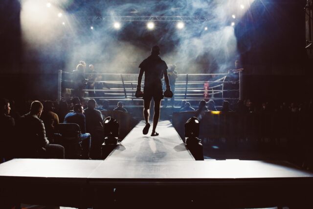 Photo by Attentie Attentie man standing and walking going on boxing ring surrounded with people