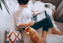 The Future of Remote Work is in Luxurious Destinations and Work-Life Balance woman in white long sleeve shirt and blue denim shorts sitting on bed using tablet computer