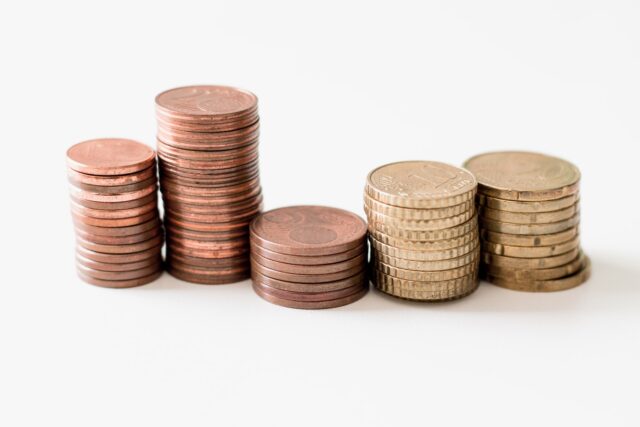 Photo by Ibrahim Rifath stacked round gold-colored coins on white surface