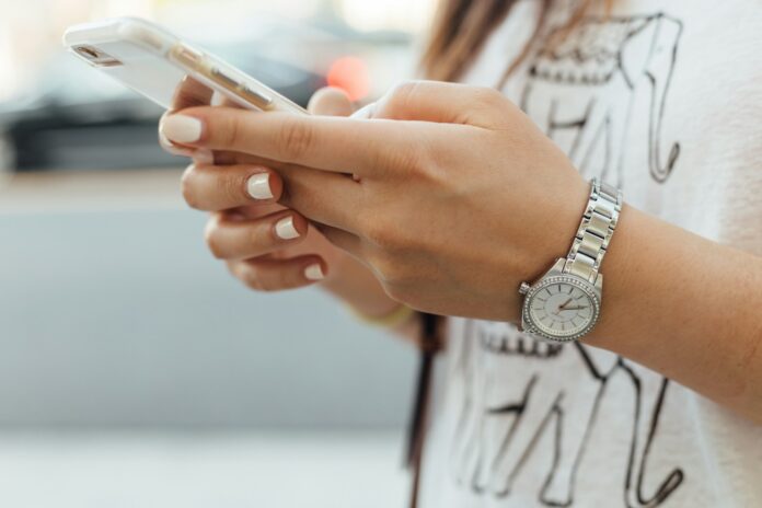 Photo by Paul Hanaoka woman holding iPhone during daytime