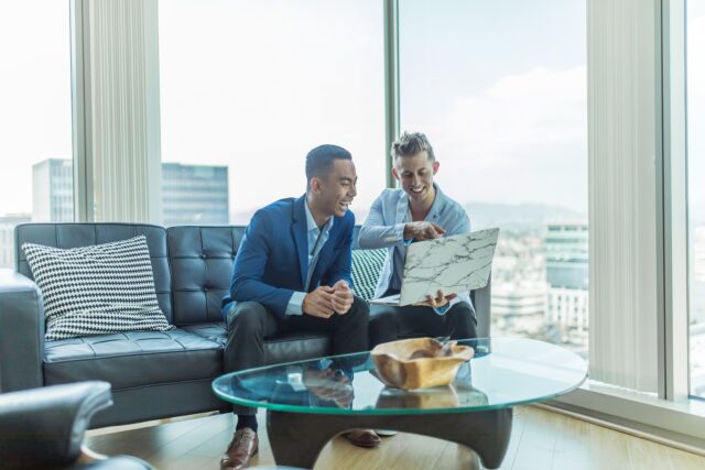 Photo by Austin Distel two men in suit sitting on sofa