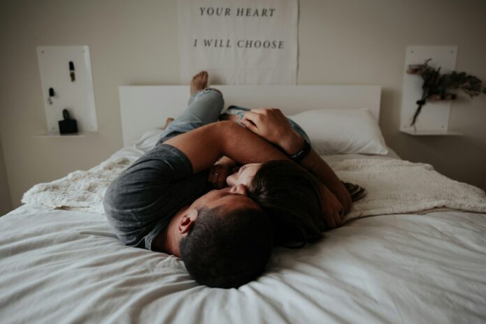 Photo by Becca Tapert A man and woman cuddling together in bed.