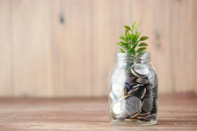 Photo by Towfiqu barbhuiya a glass jar filled with coins and a plant