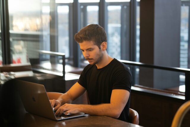 Photo by Anthony Riera man in black crew neck t-shirt using macbook