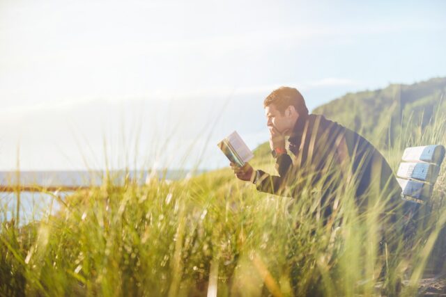 Photo by Ben White man reading book on beach near lake during daytime