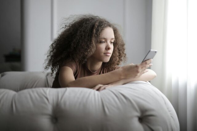 Photo by Andrea Piacquadio Photo of Woman Sitting on a Gray Bean Bag While Using Her Phone