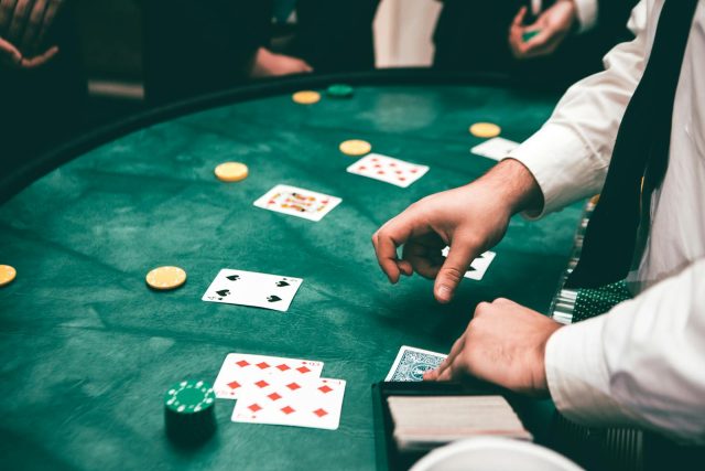 Photo by Javon Swaby Casino scene with dealer and players, featuring cards and chips, creating a suspenseful atmosphere.