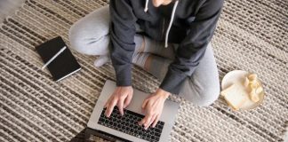 How List Cleaning Improves Email Performance and Keeps You Out of Spam Woman in casual wear working remotely on a laptop, with a notebook and snack nearby.