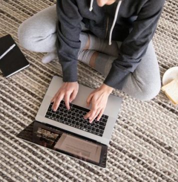 How List Cleaning Improves Email Performance and Keeps You Out of Spam Woman in casual wear working remotely on a laptop, with a notebook and snack nearby.