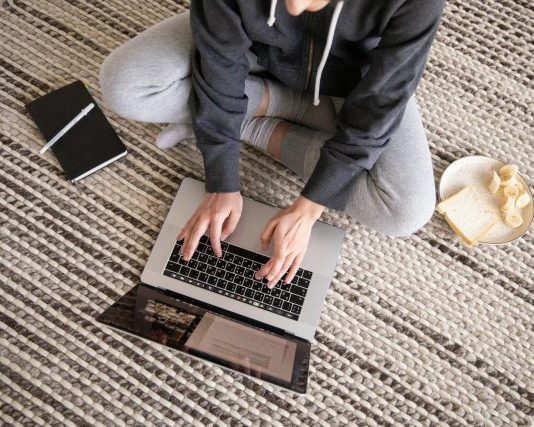 How List Cleaning Improves Email Performance and Keeps You Out of Spam Woman in casual wear working remotely on a laptop, with a notebook and snack nearby.