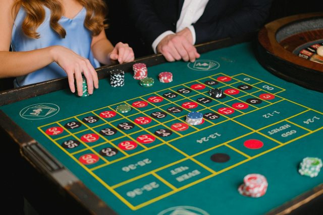 Photo by Anna Shvets Captivating scene of a casino roulette table with gamblers placing their bets.