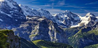 A Photographer’s Guide to Capturing the Alps green grass field near snow covered mountain under blue sky during daytime