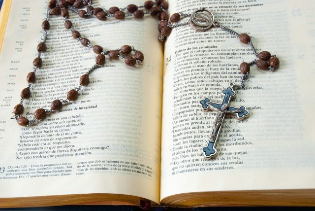 Photo by Lennon Caranzo silver cross pendant necklace on book page